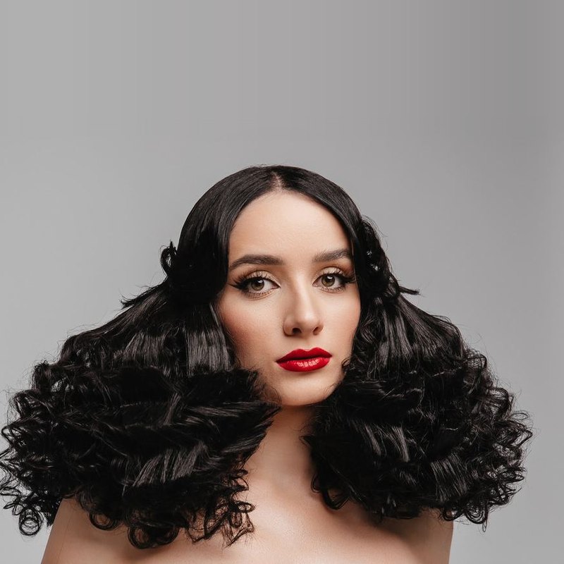 Coafură cu bucle negre voluminoase și machiaj de scenă, portret frontal